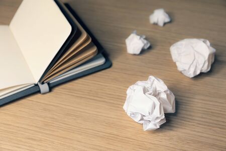 Office desk table with note book and waste paper ballsの写真素材