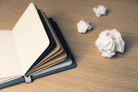 Office desk table with note book and waste paper ballsの写真素材