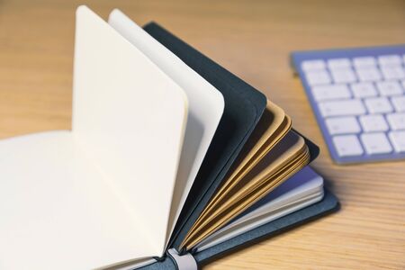 Office desk table with supplies. note book open and keyboardの写真素材