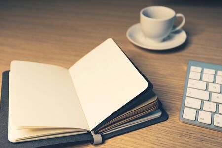 Office desk table with supplies. Cup, note book open and keyboard