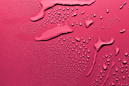 Close up of water drops on smooth surface, pink background