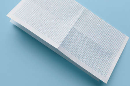 Close-up of squared paper sheet, isolated on blue