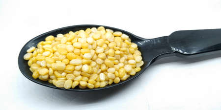 A picture of split moong daal on black spoon