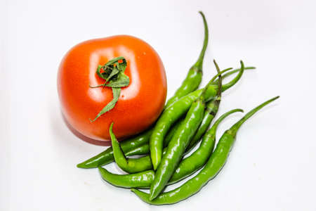 A picture of green chilies with fresh tomatoの写真素材