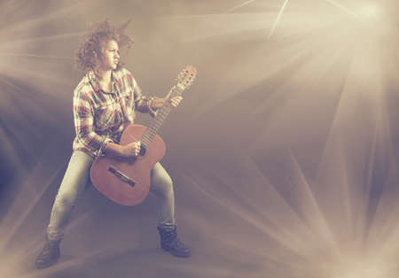 Teenager with a messy hair playing heavy the classical guitarの写真素材