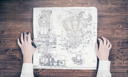 Young woman studying a blueprint of engine schemeの写真素材