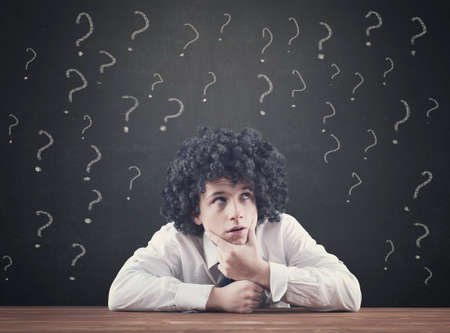 Confused teenager and blackboard drawing many question mark over him