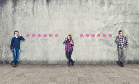 Teenagers communicating on phone next to a wall painted with dots ,modern technology. The concept of communicationの写真素材