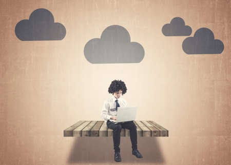 Teenager working on laptop and clouds painted on wallの写真素材