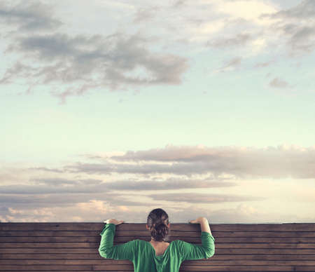 The young girl looking over the top of a wood fence.の写真素材
