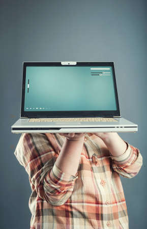 Young girl holding a laptop in front of her headの写真素材