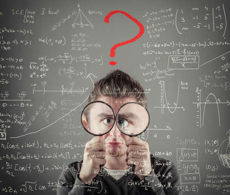 Helpless man is looking through two magnifying glasses to mathematical formulas and problems. Red question mark .の写真素材