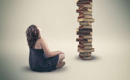 The attractive young girl  looking at a stack of booksの写真素材
