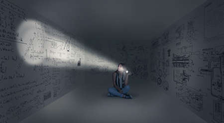 Young girl in center of a dark room looking to math formulas using an flashlight, izolated in a room with a sketch drawn on the wallの写真素材