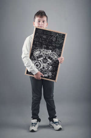 Kid holding a blackboard with a sketch drawn of an engine and math formulasの写真素材