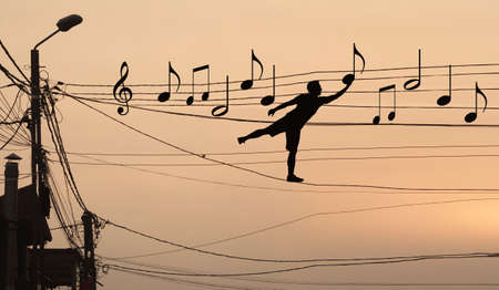 Sillouthe of a man putting music notes on wires . Concept of a crazy composerの写真素材