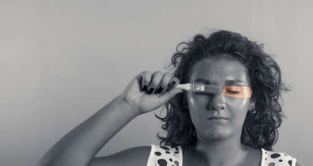 Black and white portrait with a woman giving color to her face with a brushの写真素材