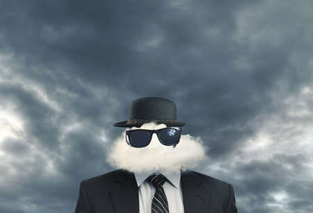 Businessman with a cloud in place of his head wearing a hat and sun glassesの写真素材
