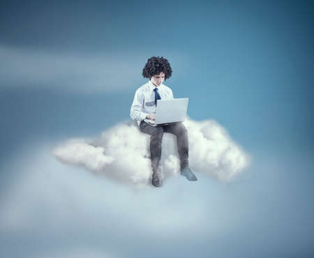 Teenager working on laptop and up on cloudの写真素材