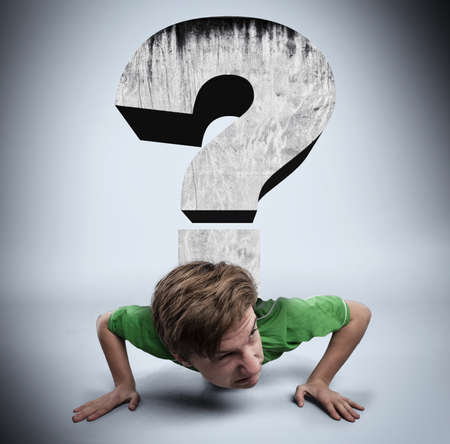 Young man is pushed by a question mark to ground.の写真素材