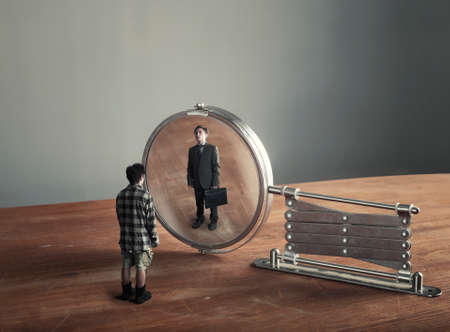 Casual man looking into the mirror and see himself as a businessman , suggesting future aspiration and social change.の写真素材