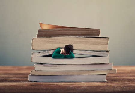 Young girl sleeping between pages of a book.の写真素材