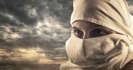 Beautiful girl go through the desert with her head covered.の写真素材