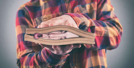 Face of a man crushed by a book  . Book covering the entire head suggesting stress.の写真素材