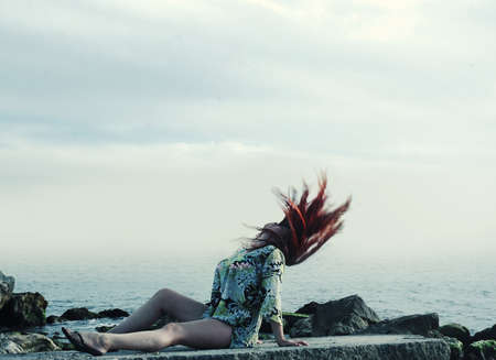 Young girl lying on the rocks near the ocean.の写真素材