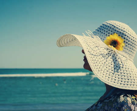 Beautiful woman wearing a hat near the sea.の写真素材