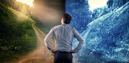 Man standing in front of two different roads, one road warm climate and one road cold climate. The...