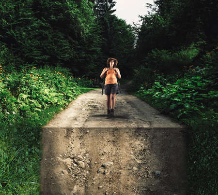 Young girl walking in forest on a road bent down.