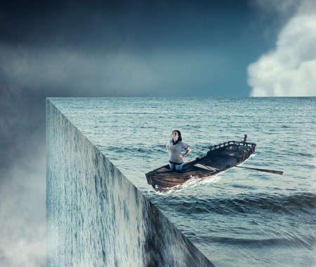 Girl sail on a boat in the ocean, reaching the edge of the ocean. End of the world concept.
の写真素材