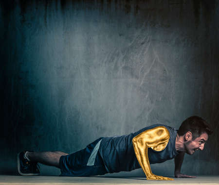 Athlete male in sportswear doing push ups, golden arm.の写真素材