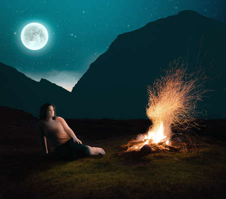 Woman contemplating next to the fire camp - camping alone.の写真素材