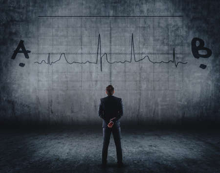 Businessman looking at a graph between a painting on a wallの写真素材