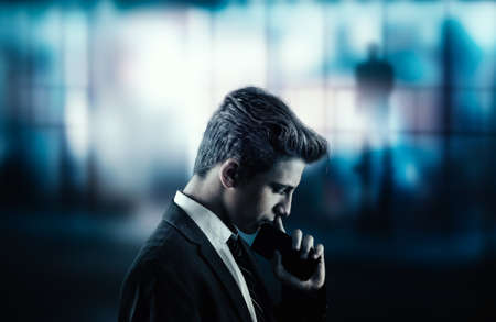 Thoughtful bussinessman with a phone and a city view suggesting a very important decisionの写真素材