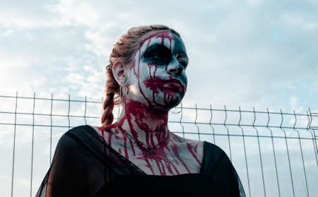 Portrait of a gothic girl wearing a black dress and a bloody make up.Halloween theme.の写真素材