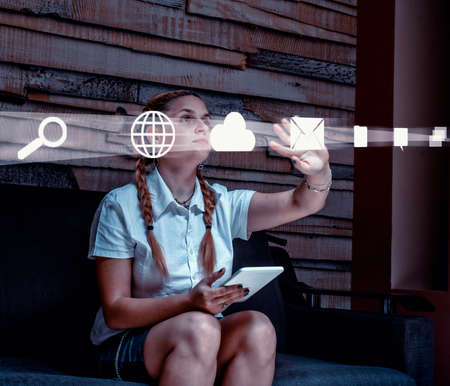 Young woman using tablet and hologram icons at home.Futuristic user interface.