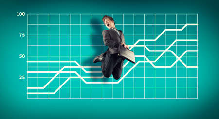 Business man jumping on a simple background with a graph painted on it. The concept of progress.