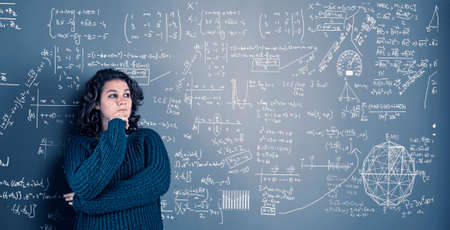 Young woman solving math problema drawn on wall.