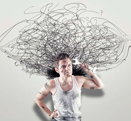 Confused mechanic in front of a white wall drawn with chaotic lines.The concept of confusion.