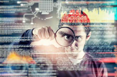 Man looking through magnifying glass to a futuristic interface.の写真素材