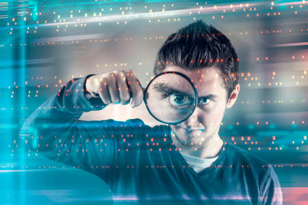 Man looking through magnifying glass to a futuristic interface.