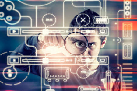Man looking through magnifying glass to a futuristic interface.