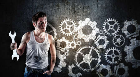 Confused mechanic holding a wrench in front of a blackboard, drawn with a engine wheels gear.の写真素材