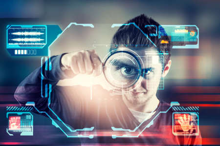 Man looking through magnifying glass and using face recognition system.の写真素材