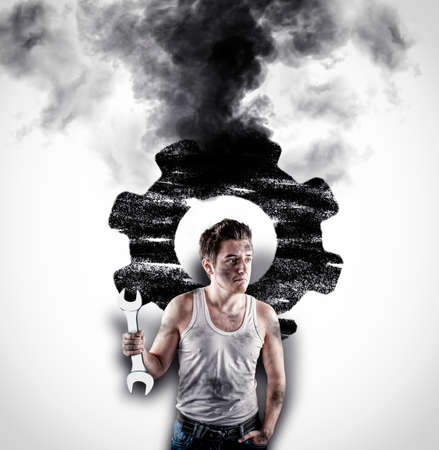 Confused mechanic holding a wrench in front of a white wall. Wall drawn with a broken engine wheel .の写真素材