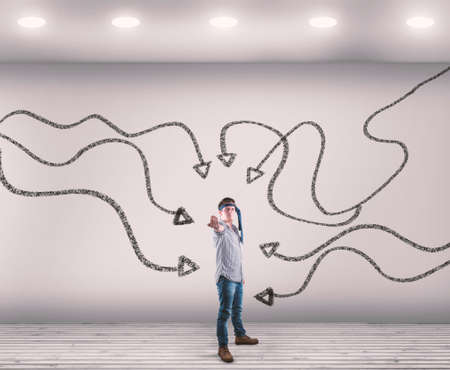 Confident man in a white room with arrows drawn on wall leading to him.の写真素材