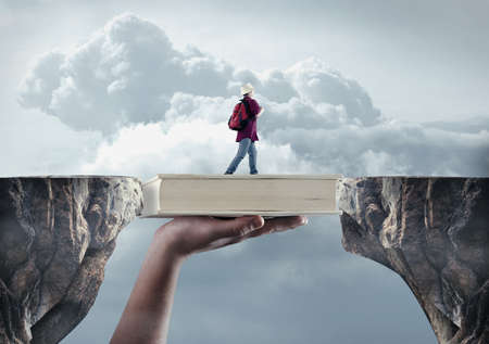 Young man passes from a peak to another on a book. The concept of scholarship.の写真素材